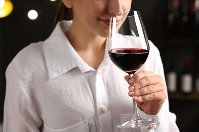 Photo of Professional sommelier tasting red wine in glass indoors, closeup