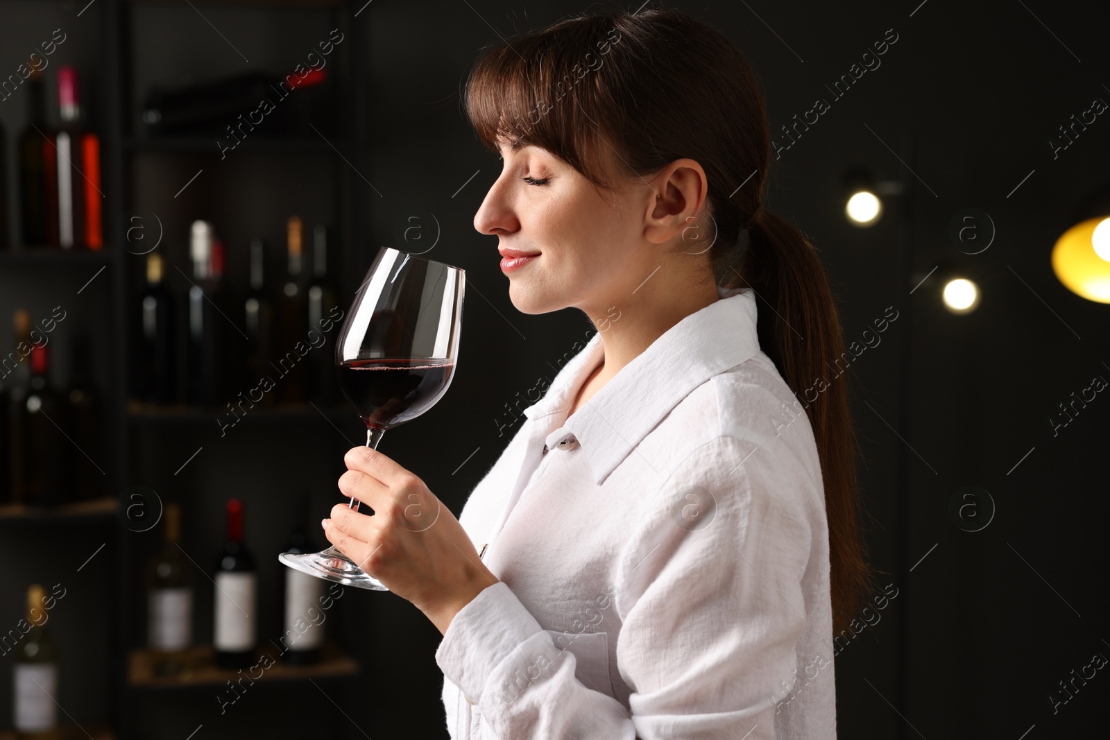 Photo of Professional sommelier tasting red wine in glass indoors