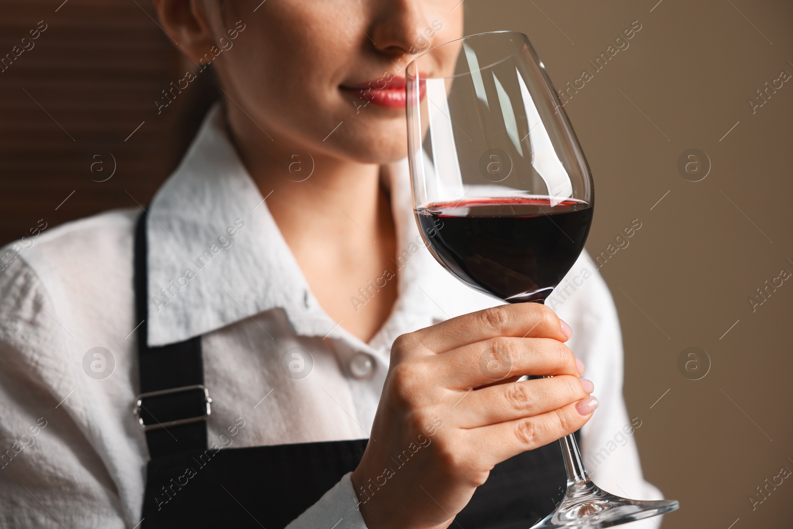 Photo of Professional sommelier tasting red wine in glass indoors, closeup