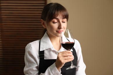 Photo of Professional sommelier tasting red wine in glass indoors