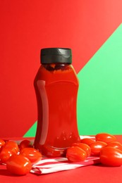 Photo of Bottle of ketchup and tomatoes on color background