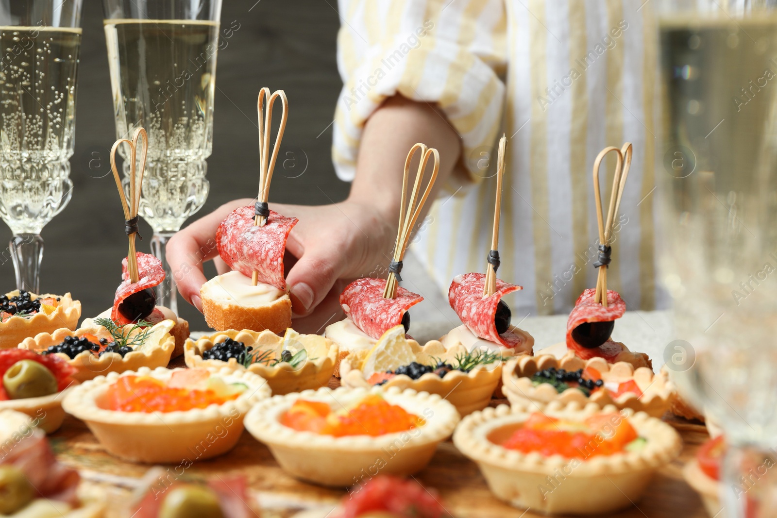 Photo of Woman taking tasty canape at table, closeup