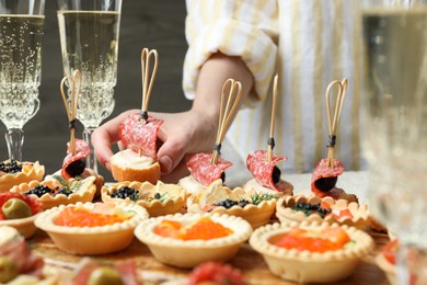 Photo of Woman taking tasty canape at table, closeup