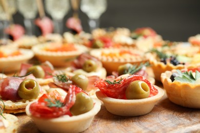 Photo of Many different tasty canapes on wooden board, closeup