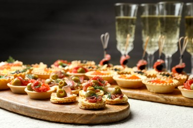 Photo of Many different tasty canapes and wine on white table