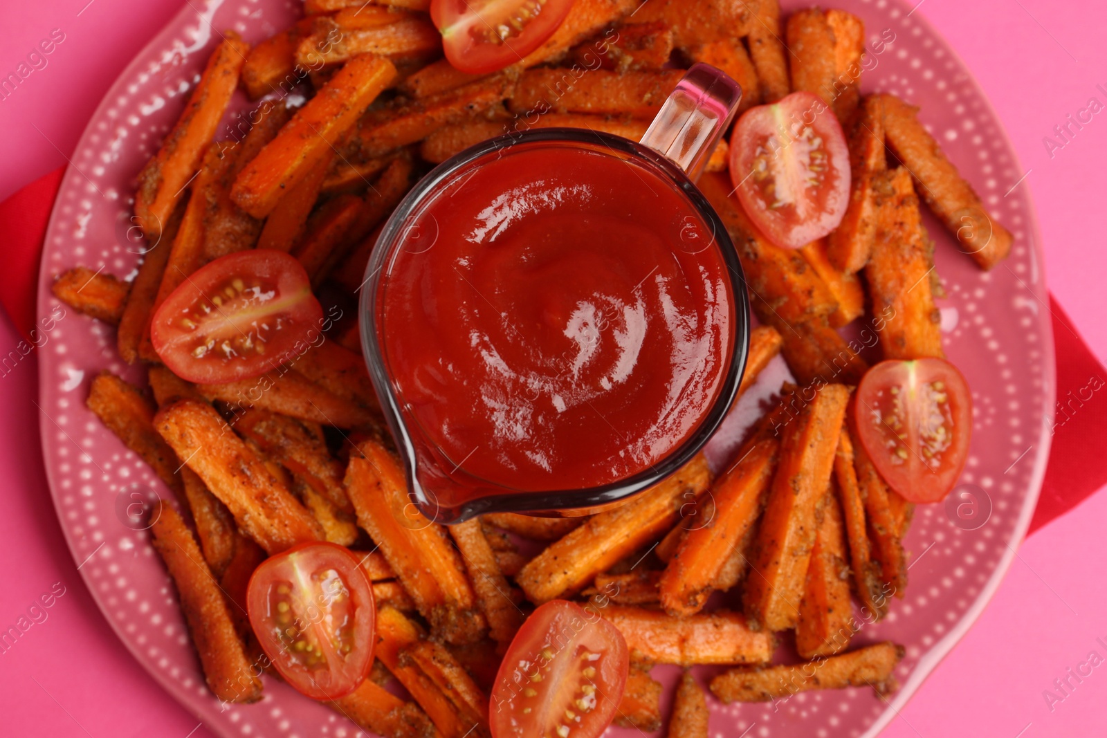 Photo of Tasty ketchup, tomatoes and fried carrots on pink background, top view