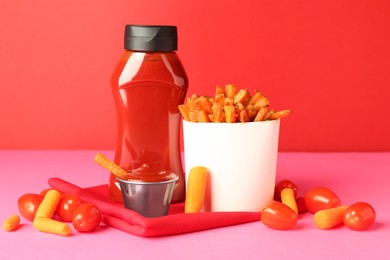 Photo of Tasty ketchup, tomatoes and fried carrots on color background