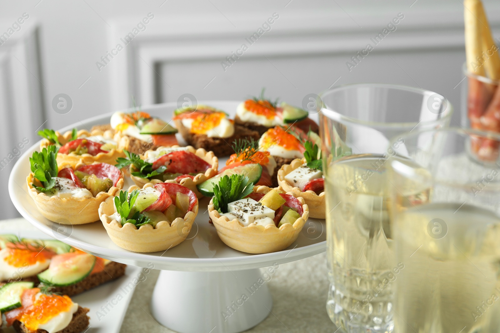 Photo of Many different tasty canapes and wine on white table, closeup