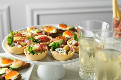 Photo of Many different tasty canapes and wine on white table, closeup