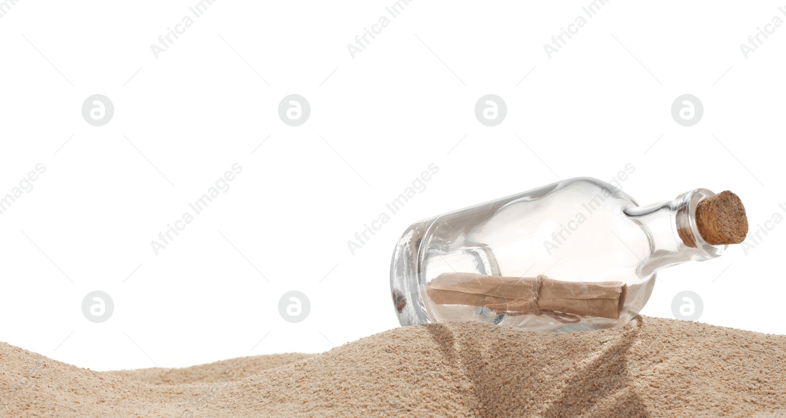 Photo of Rolled letter in corked glass bottle on sand against white background