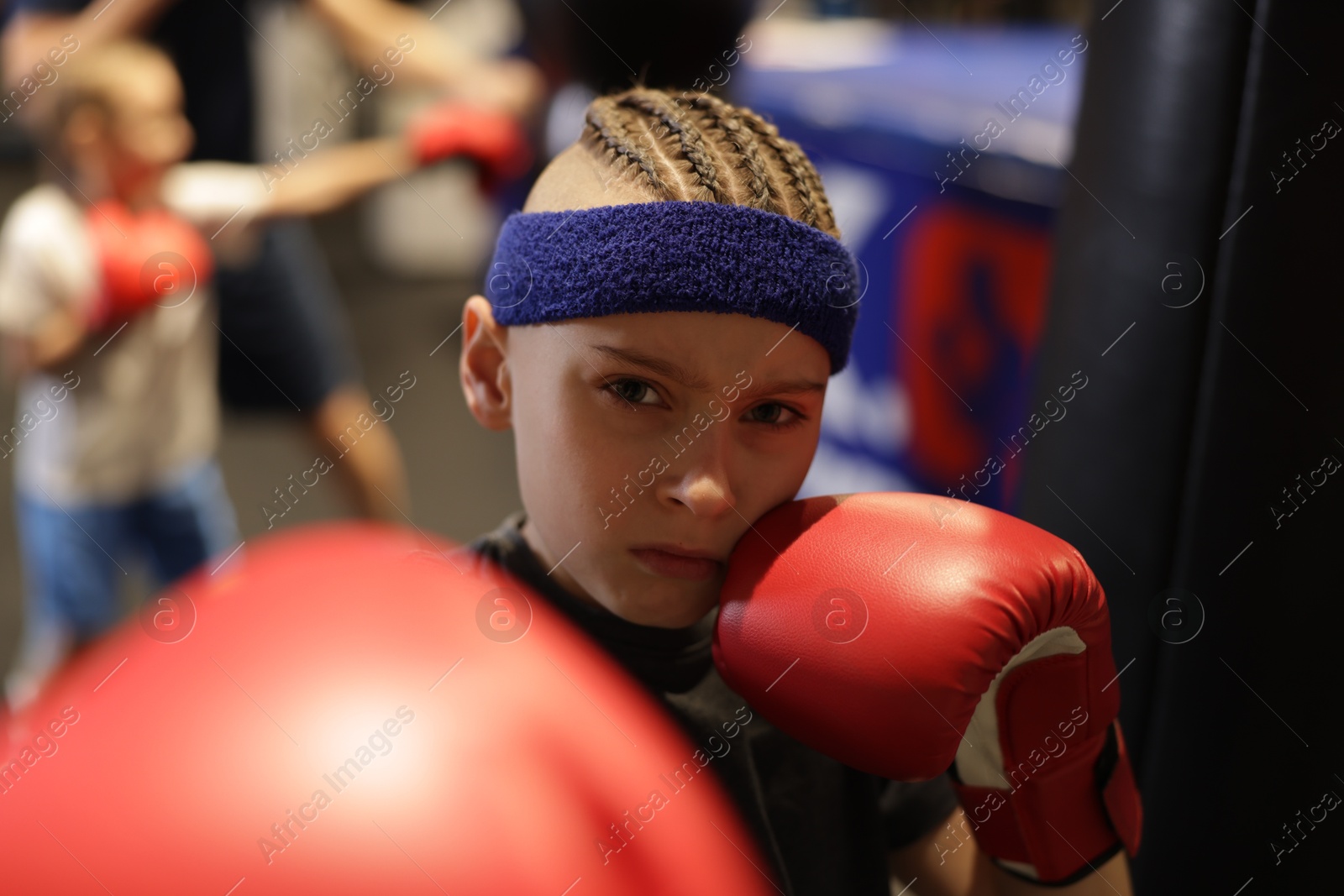 Photo of Boy in protective gloves during boxing practice at training center