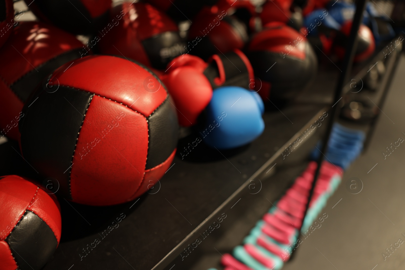 Photo of Different sport equipment on shelfs in training center, closeup