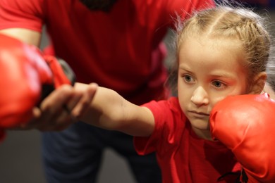 Photo of Girl in protective gloves having boxing practice with her coach at training center