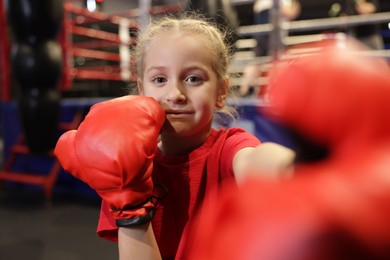 Photo of Girl in protective gloves having boxing practice indoors