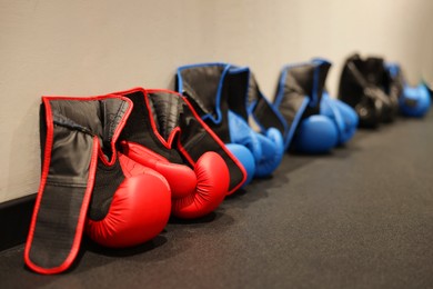 Photo of Different protective boxing gloves near light wall indoors