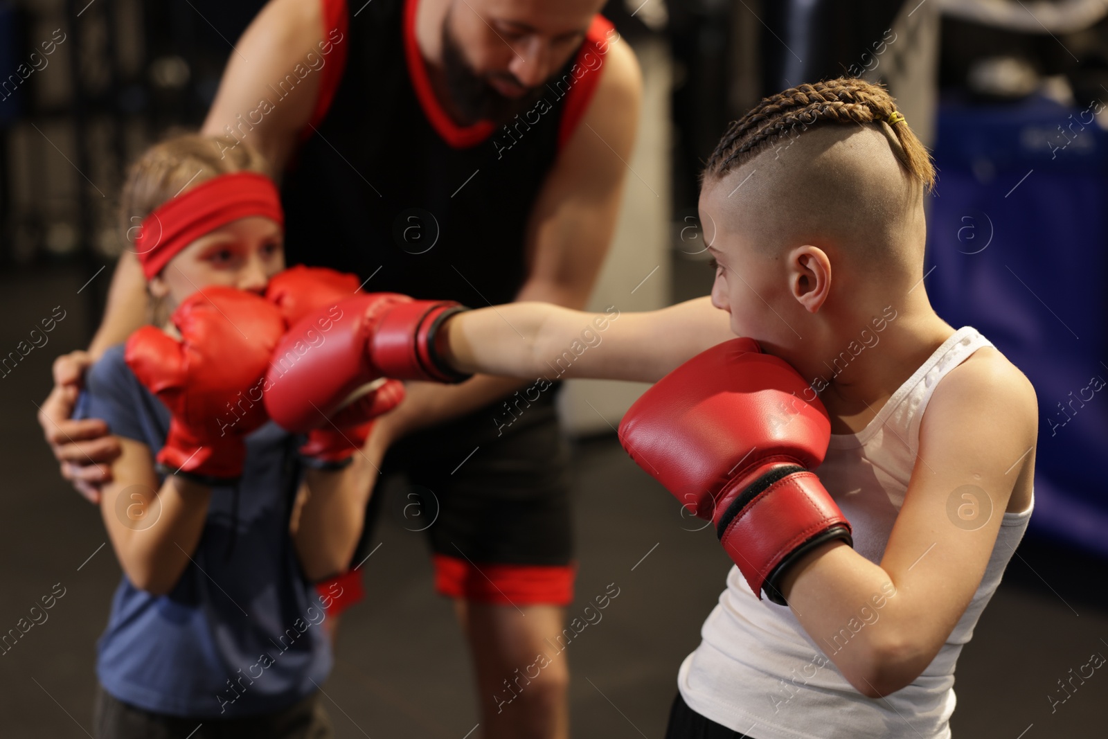 Photo of Children having boxing practice with their coach in training center, selective focus