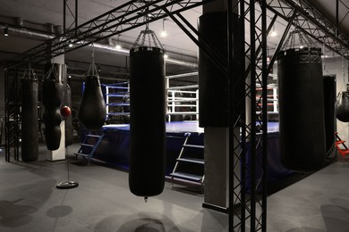 Photo of Punching bags and boxing ring in training center