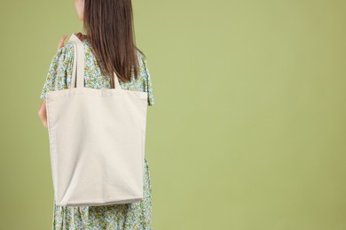 Photo of Woman with blank shopper bag on color background, back view. Mockup for design