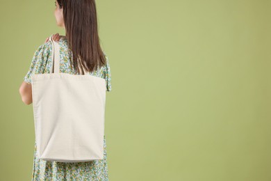 Photo of Woman with blank shopper bag on color background, back view. Mockup for design