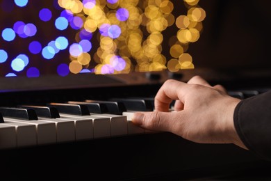 Photo of Man playing piano against blurred lights, closeup. Bokeh effect