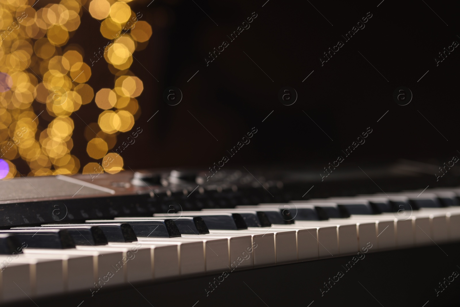 Photo of Piano against blurred lights, closeup with space for text. Bokeh effect