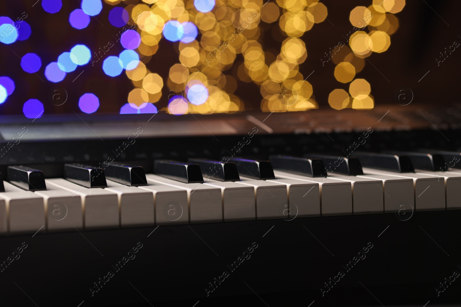 Photo of Piano against blurred lights, closeup. Bokeh effect