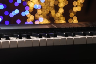 Photo of Piano against blurred lights, closeup. Bokeh effect