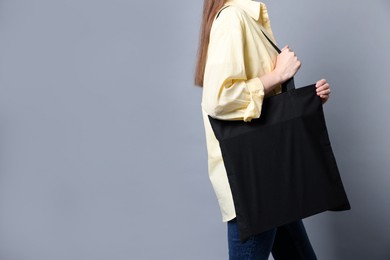 Photo of Woman with blank shopper bag on grey background, closeup. Mockup for design