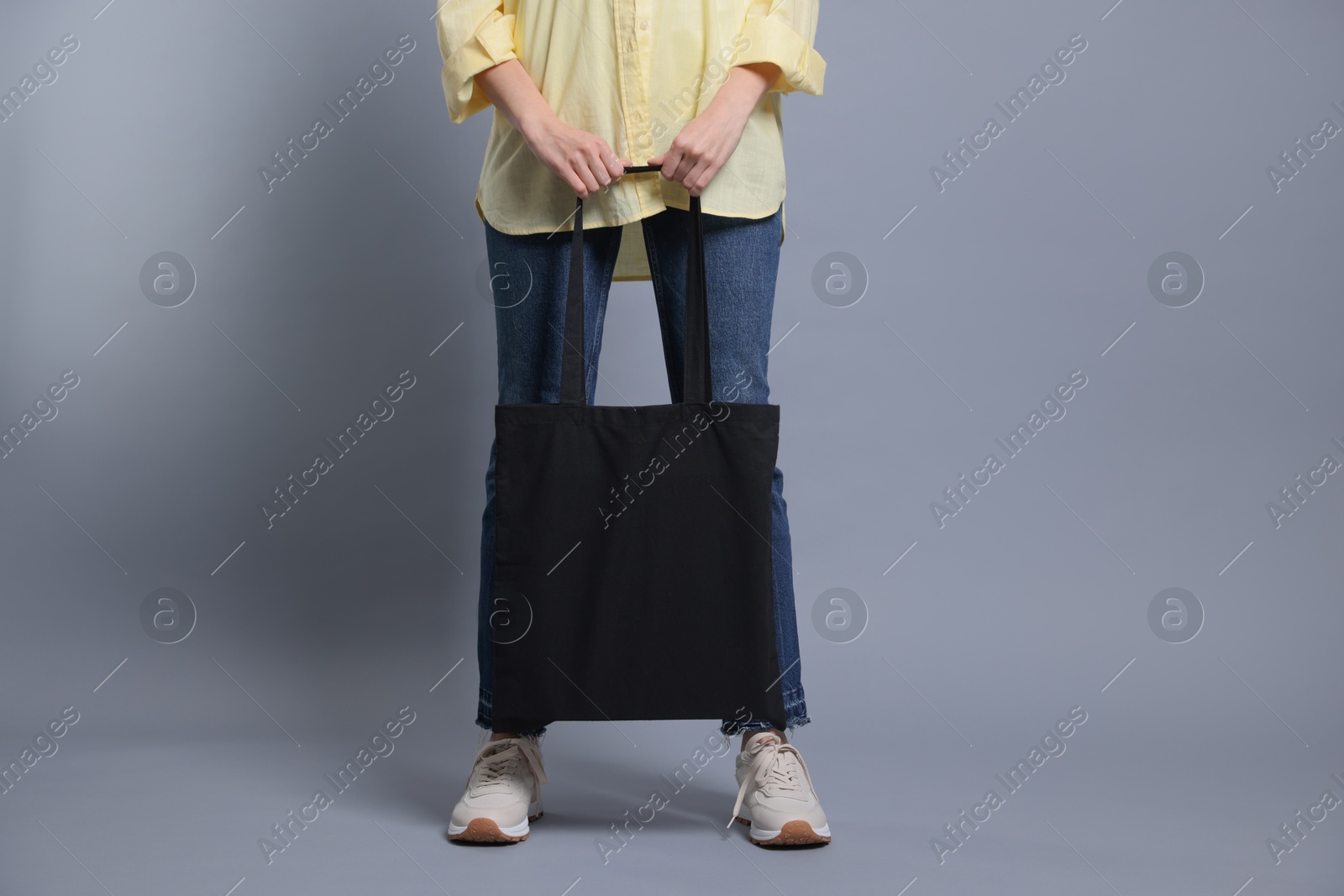 Photo of Woman with blank shopper bag on grey background, closeup. Mockup for design