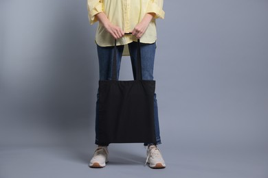 Photo of Woman with blank shopper bag on grey background, closeup. Mockup for design