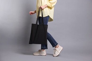 Photo of Woman with blank shopper bag on grey background, closeup. Mockup for design