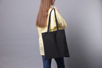 Photo of Woman with blank shopper bag on grey background, closeup. Mockup for design