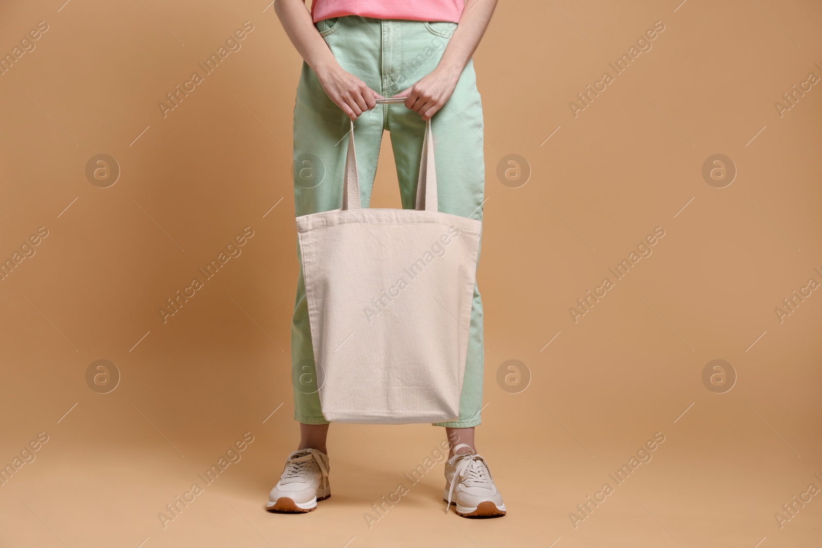 Photo of Woman with blank shopper bag on beige background, closeup. Mockup for design