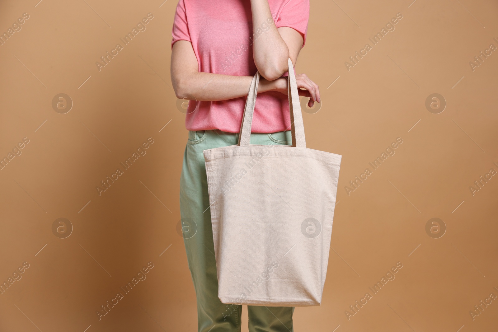 Photo of Woman with blank shopper bag on beige background, closeup. Mockup for design