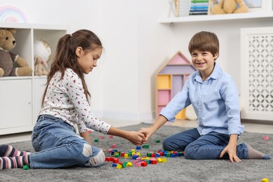 Children playing with colorful cubes on floor indoors