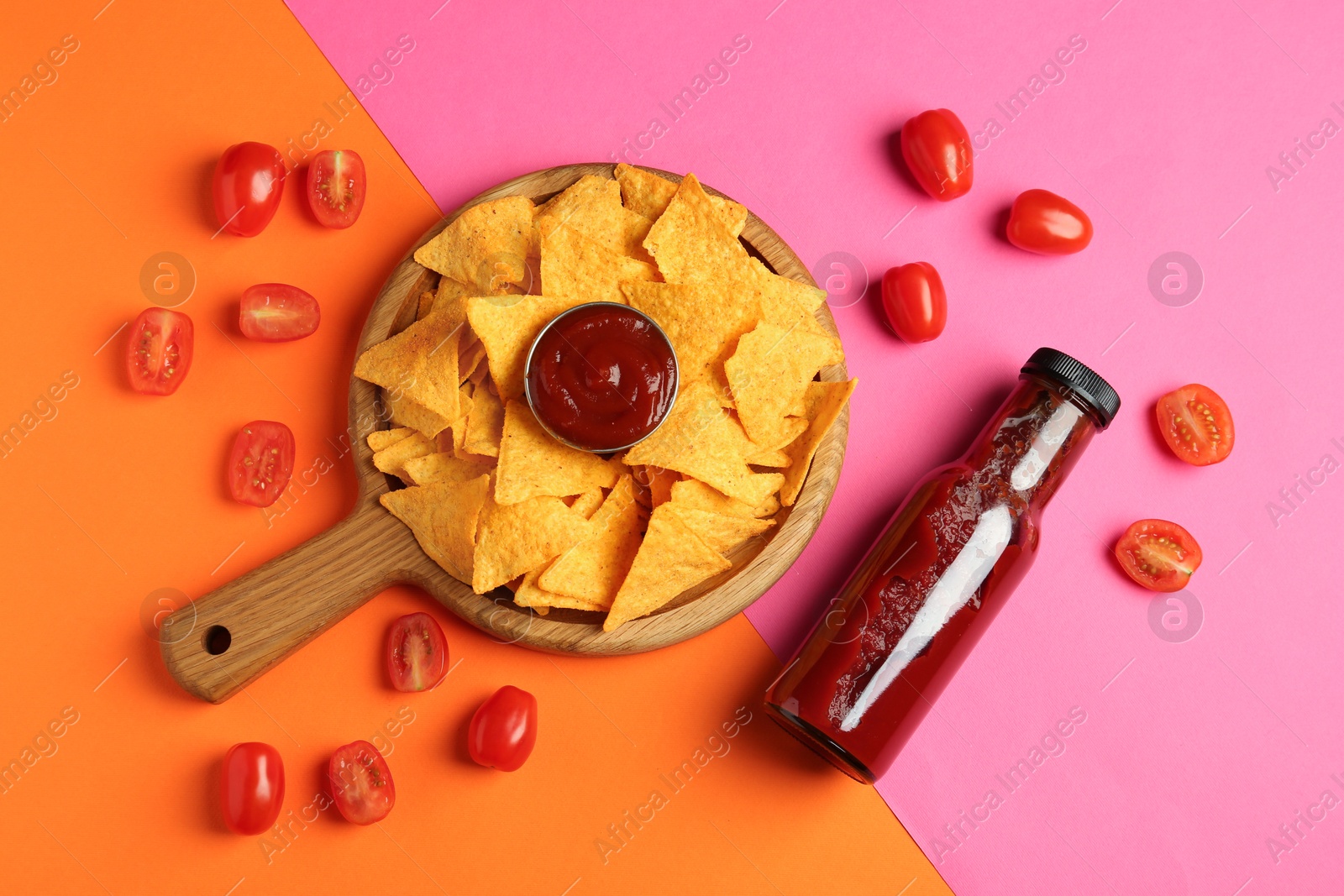 Photo of Tasty ketchup, tomatoes and nachos on color background, flat lay