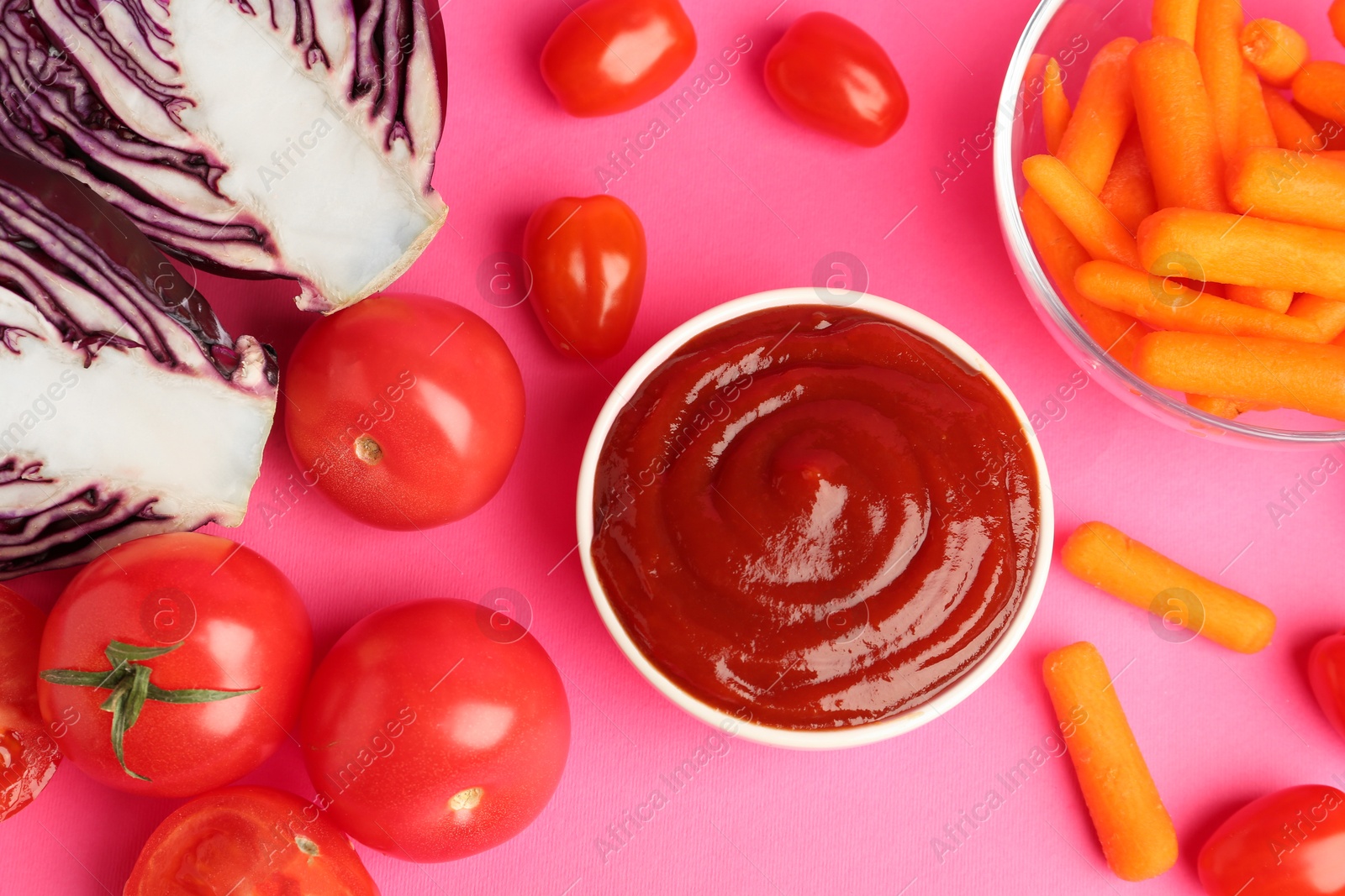 Photo of Tasty ketchup and vegetables on pink background, flat lay