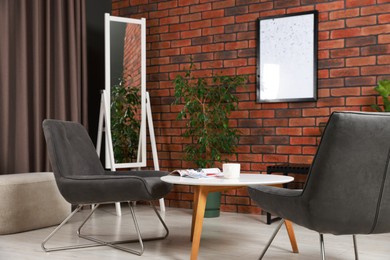 Photo of Soft armchairs, coffee table, mirror and houseplants in cozy living room. Interior design