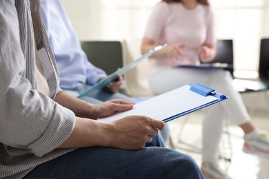 Photo of People with clipboards during meeting indoors, closeup