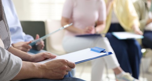 Photo of People with clipboards during meeting indoors, closeup