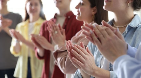 People applauding during meeting indoors, closeup view