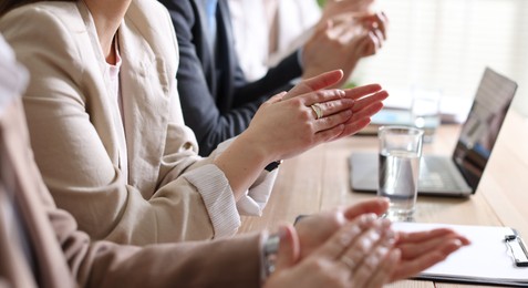 People applauding at table in office, closeup