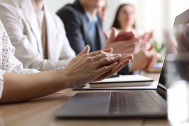 People applauding at table in office, closeup