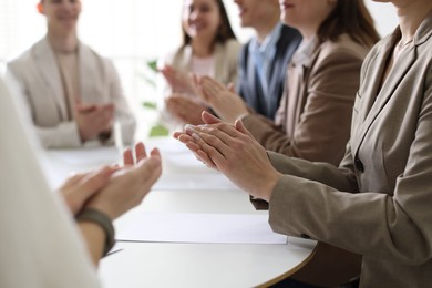 People applauding at table in office, closeup