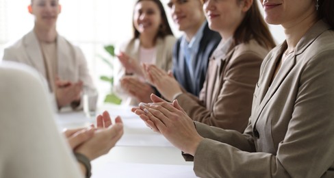 People applauding at table in office, closeup