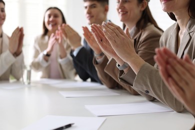 People applauding at table in office, closeup