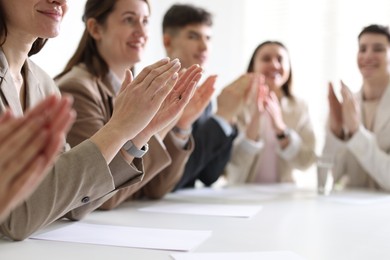 People applauding at table in office, closeup