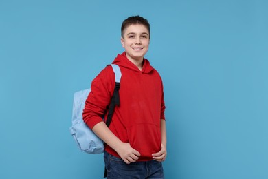 Photo of Teenage boy with backpack on light blue background