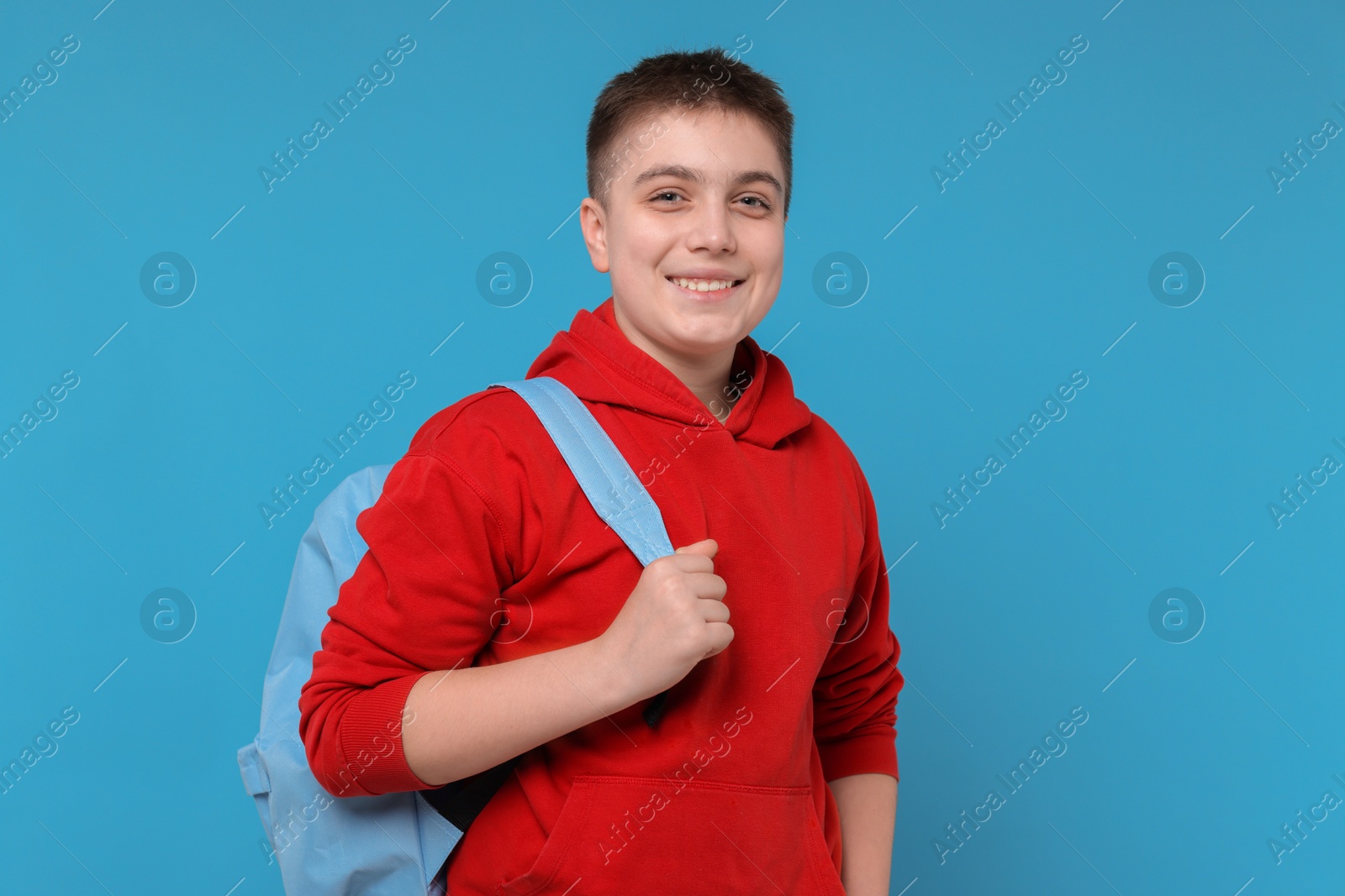 Photo of Teenage boy with backpack on light blue background