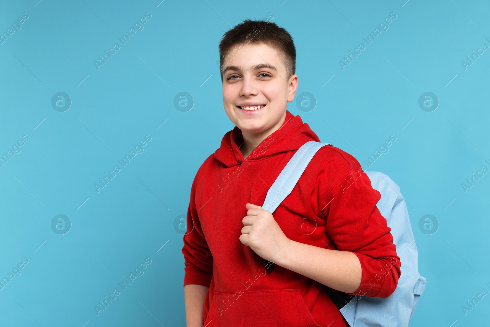 Photo of Teenage boy with backpack on light blue background, space for text